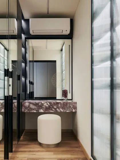 A vanity nook with a beautiful purple-veined marble countertop. The mirrored wardrobe doors and fluted glass partition create a bright and textured space.