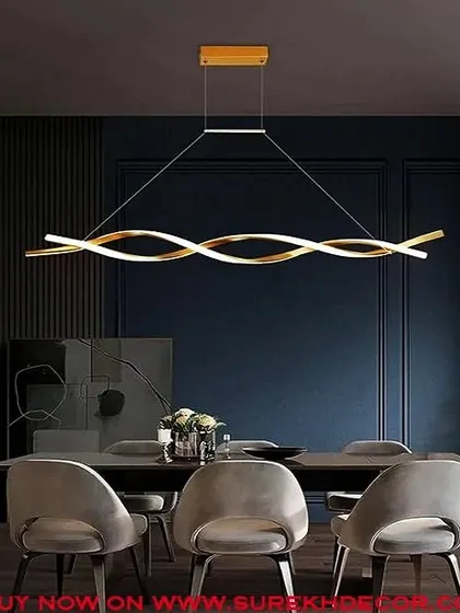 This modern curled LED chandelier in a golden finish is perfect for hanging over a dining table. Its fluid, sculptural form adds an artistic element to the room, as seen in this dark, moody dining space with plush grey chairs.