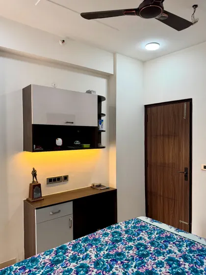 A compact bedroom setup with a wall-mounted study or storage unit. The under-cabinet lighting provides task lighting without taking up desk space.