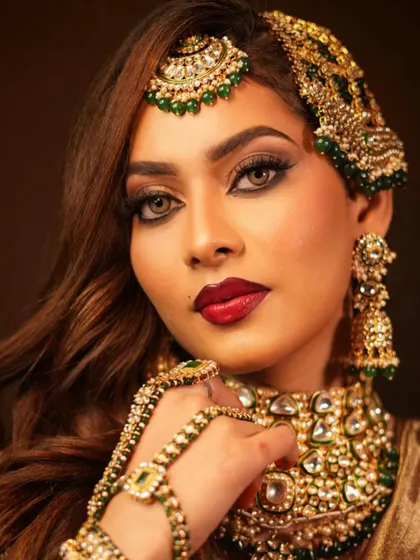 A striking close-up of a bridal look, focusing on the intense gaze, bold red lips, and the intricate details of the passa and maang tikka.