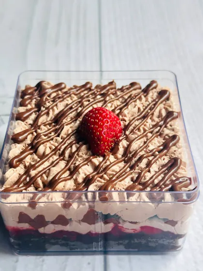 A side view of the Choco Nutella Mousse tub with strawberries. You can see the layers of dark chocolate, strawberry compote, and creamy Nutella mousse.