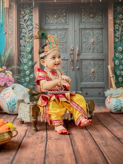 A side profile of little Krishna sitting happily on the cot, looking towards the light.
