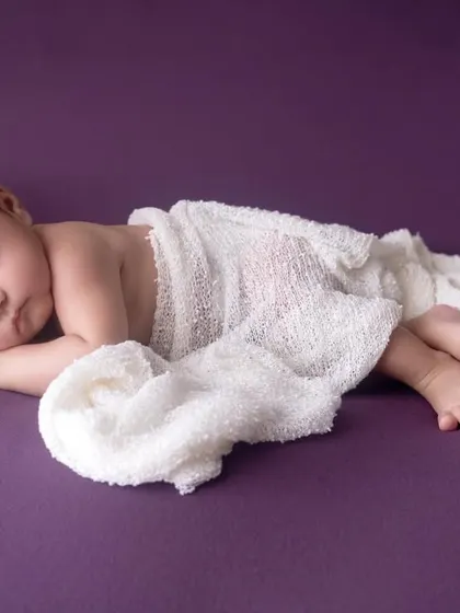 A beautifully simple pose, with the newborn wrapped loosely in white gauze. This minimalist approach keeps the focus on your baby's natural and peaceful state.