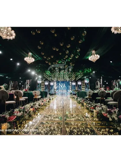 The grand entrance to the Sangeet, where a fairy-lit glass aisle is flanked by lush floral arrangements, leading the eye towards the main stage. This view captures the scale and immersive quality of the world we built for this event.