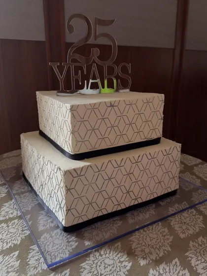 This two-tier corporate anniversary cake celebrates 25 years of excellence with a sharp, geometric pattern and a custom silver topper, reflecting a professional and modern brand.
