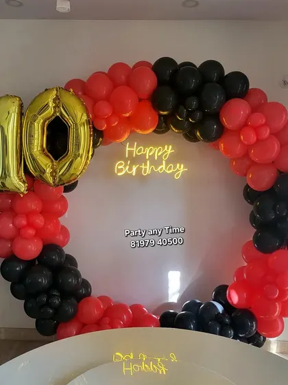 A bold red and black circular balloon arch for a 10th birthday party.