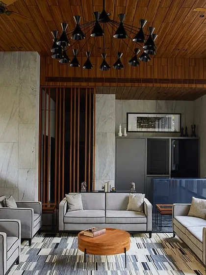 A full view of the garden lounge seating area, which includes a small pantry-bar and looks out onto the private pool area through large glass doors.