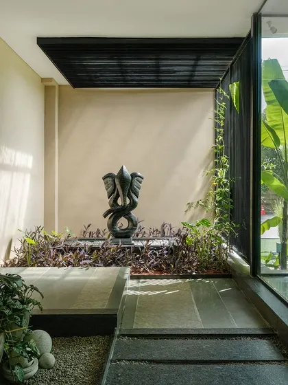 A duplicate view of the Ganesha fountain courtyard, emphasizing the textures of the stone path, water, and foliage.