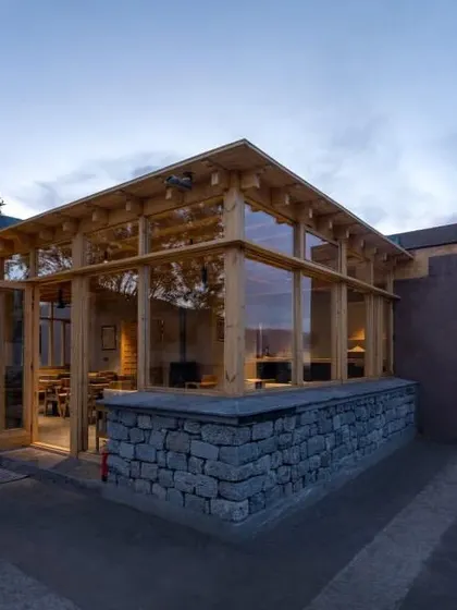 Another exterior shot of the Postcard hotel, highlighting its simple, elegant form. The structure is built with local stone and wood, grounding it in the region's vernacular building traditions.