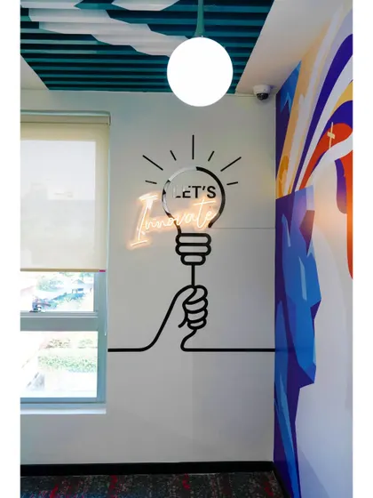 "Let's Innovate" is the message of this neon and vinyl wall graphic. Placed in a corner nook, it turns a simple space into a motivational spot for creative thinking.