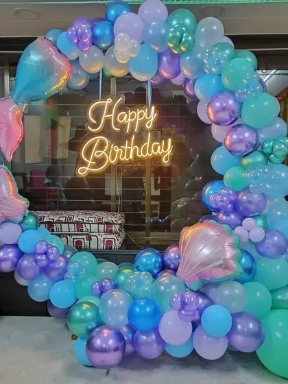 A mermaid-themed birthday with a circular balloon arch in ocean colors and mermaid tail foil balloons.