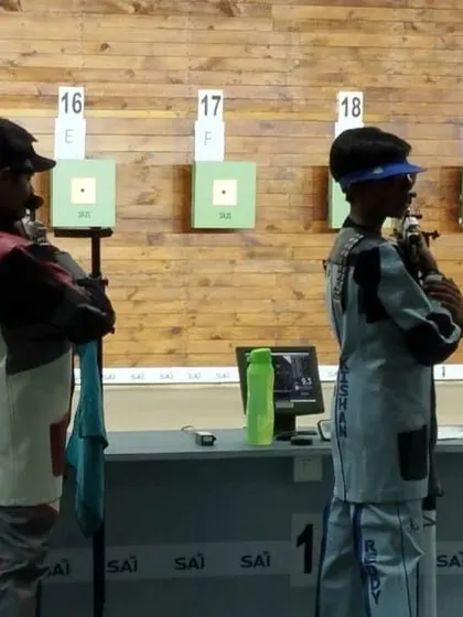 Two young shooters stand ready at their lanes during a championship, showcasing the mental preparation we instill in our athletes.