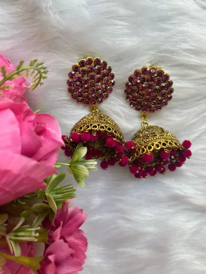 A beautifully styled shot of the pink and gold jhumkas against a floral background, highlighting their festive appeal.