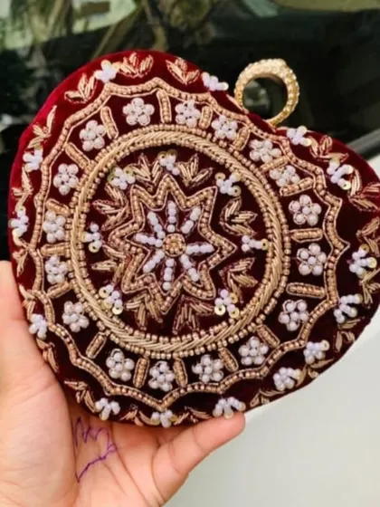 This heart-shaped clutch in deep red velvet shows the intricate beadwork and embroidery I do. Even without names, the detailed craftsmanship makes it a stunning bridal accessory.