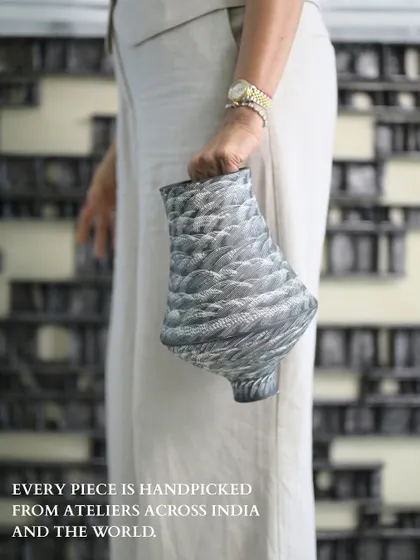 Every piece is handpicked from ateliers across India and the world. Here, I am holding one of my favorite finds, a vase with a feathered texture that feels both ancient and utterly modern.
