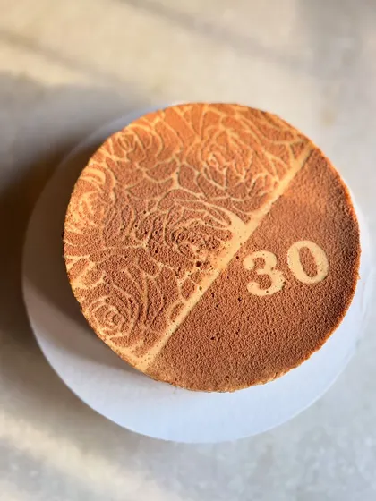 This is my bestseller for a reason: the boozy coffee baked yogurt cake. It's creamy, addictive, and a bit lighter than a traditional cheesecake. I can customize the top with stencils for any occasion, like this 30th birthday celebration.