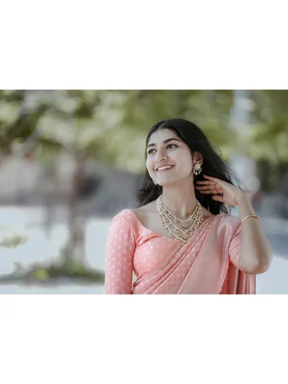 A joyful and radiant portrait. Her smile and the way she touches her hair feel spontaneous and full of life, making for a very engaging and happy image.