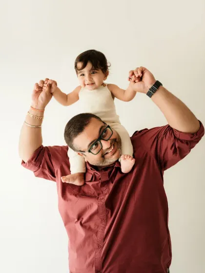 A proud dad gives his little one a shoulder ride. This is a fun and classic pose for a father and child photoshoot.