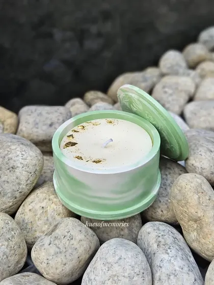 This round candle with a matching lid is shown in a soft green marble pattern. The lid helps to preserve the scent and can be used to safely extinguish the flame.