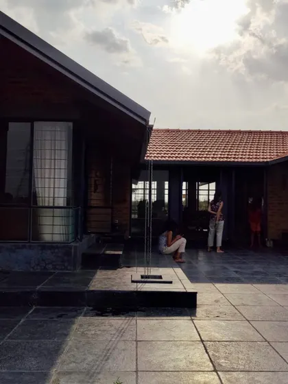 The central courtyard of the NallaNela farmhouse is a simple, open space for family activities. A rain chain, a traditional element, guides water from the roof to the ground in a visually pleasing way.