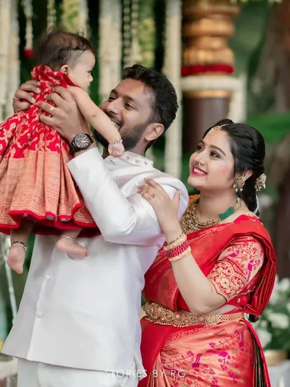 A joyful family moment. The father lifts his child, showing off their coordinated red and white outfits, designed by us for this happy occasion.