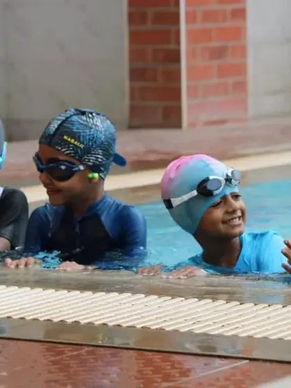 Taking a quick break at the poolside. Our lessons balance active instruction with moments for rest and social interaction, ensuring kids stay engaged and energized.