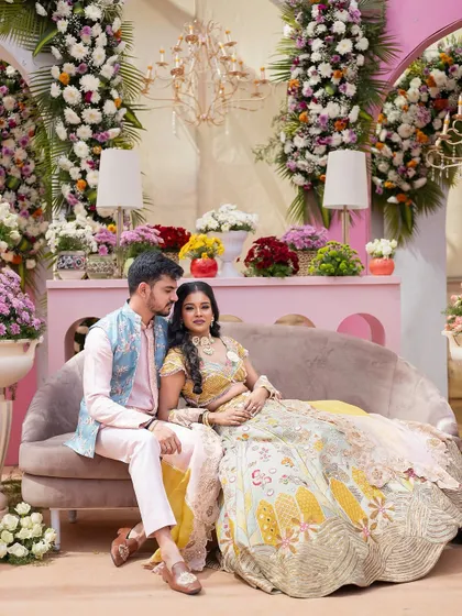 A beautiful couple moment captured against a backdrop of pastel pink architecture and towering floral arrangements. The setting is soft, romantic, and perfect for a modern daytime event.
