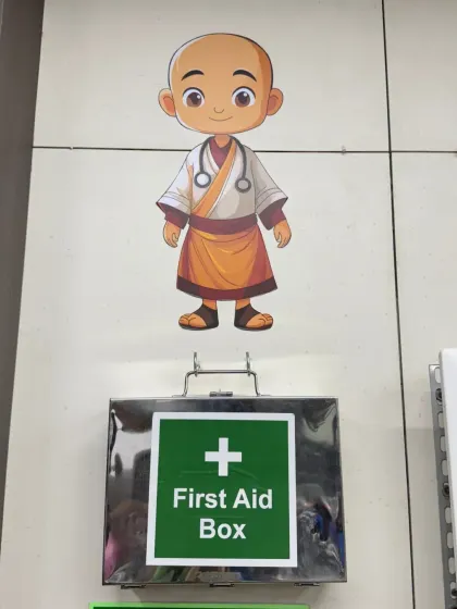 Even a first aid box can be part of the design. Here, a cute monk-as-a-doctor mural is placed just above the box, turning a mandatory safety feature into a charming and playful detail on the factory wall.