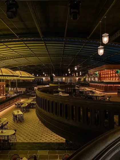 The sweeping curve of the mezzanine balcony, a key architectural feature that defines the space. This element helps to create a dynamic visual flow and offers varied perspectives of the bar below.