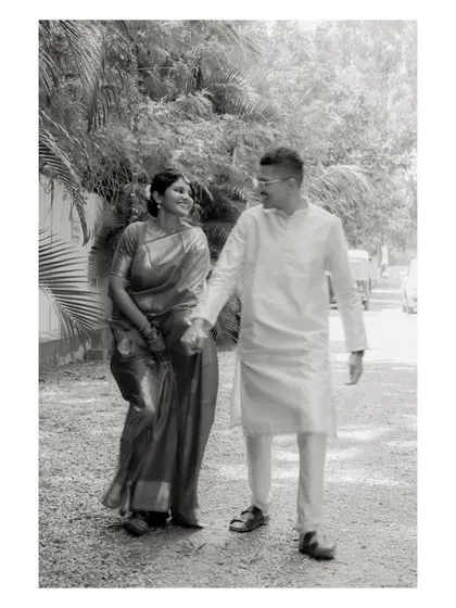 A black and white photo of a couple walking hand-in-hand. This timeless shot emphasizes the connection between them, with the natural surroundings creating a soft background.