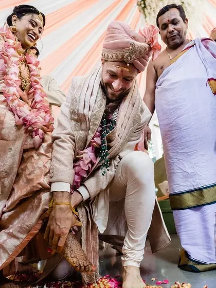 A moment of humility and tradition as the groom participates in the Kashi Yatra ritual. The smiles of the bride and family members add a layer of warmth and lightheartedness to the scene.