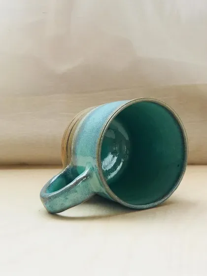 The Flow Mug on its side, showcasing its sturdy handle and the beautiful gradient of the glaze.