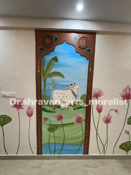 A blend of tradition and texture. We created this beautiful Pichwai-style mural featuring a sacred cow and calf, framed by an arch with lippan art details. The surrounding wall is adorned with painted lotus flowers, bringing a sense of peace and heritage to the space.
