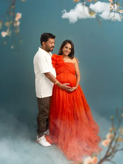 A full-length view of the couple, showing the beautiful ombre effect of the red gown. The dreamy, cloud-like effects at their feet add a touch of magic to this romantic shot.