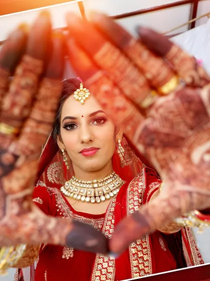 A creative bridal portrait, with the bride framing her face with her henna-covered hands.