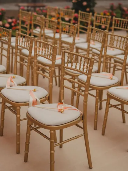 Elegant gold chairs for a ceremony, each adorned with a small bell, adding a charming and interactive element.