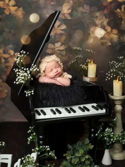 A newborn portrait with a vintage feel, featuring a baby in a lace bonnet on a piano, surrounded by candlelight. This setup is perfect for creating a timeless and classic image.