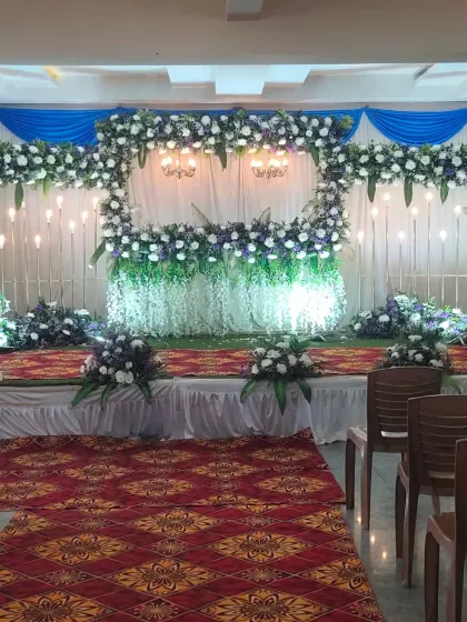 The stage setup for the Half Saree event, featuring a green grass-like floor and a white and blue floral frame.