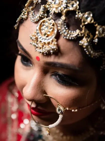 A close-up on the bride's face, highlighting her intricate matha patti and stunning eye makeup.