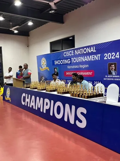The awards stage, lined with trophies, ready for the closing ceremony of the CISCE National Shooting Tournament 2024.