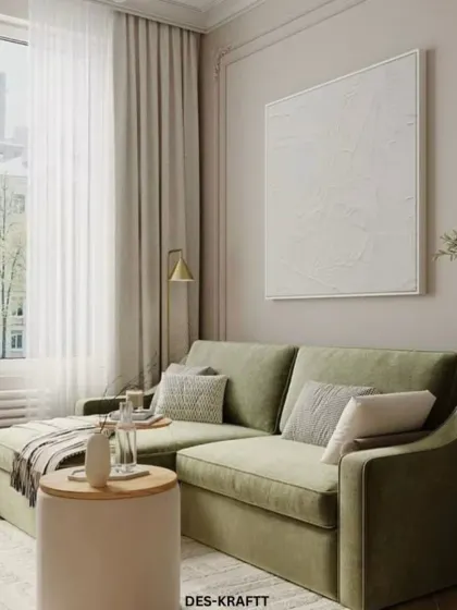 A serene living room corner featuring a soft green velvet sofa, light wood floors, and sheer curtains that flood the space with natural light, creating a calm and airy feel.