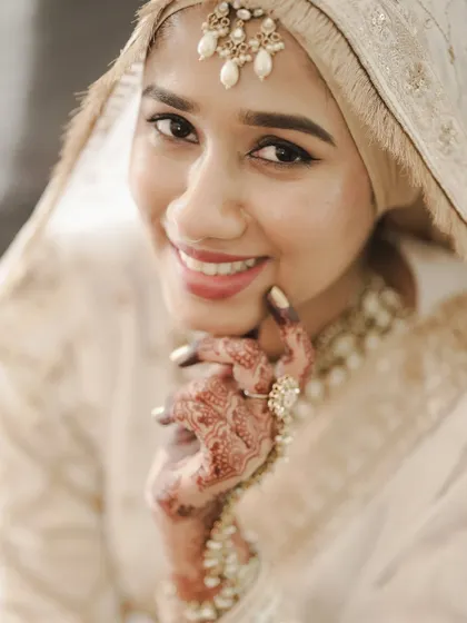 A close-up portrait of the bride, her happy smile and henna-adorned hand creating a lovely, intimate feel.