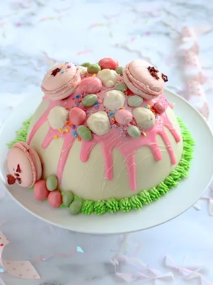 Get ready for a fun surprise with our White Chocolate Dome Piñata Cake. This isn't just a cake you cut; you get to hammer it open to reveal a cascade of delicious M&Ms hidden inside.