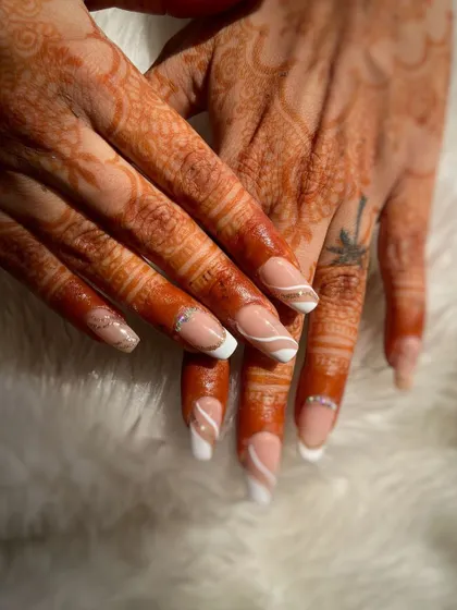 A clean and elegant French manicure with a swirl accent, perfectly complementing the bridal henna. This student work showcases precision and classic style.