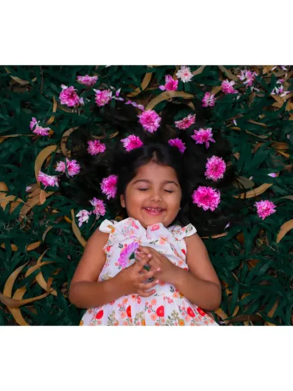 A blissful smile from a girl lying in the grass, with flowers in her hair. A perfect example of a beautiful, natural portrait.