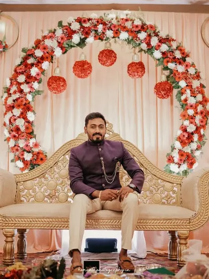 A portrait of the groom seated on the decorated stage during his engagement ceremony, looking sharp and ready for the event.