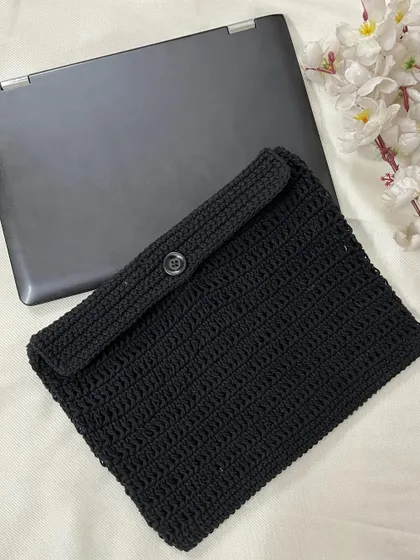 The back of the crochet laptop sleeve, showing the simple and secure button closure that keeps your device safe.