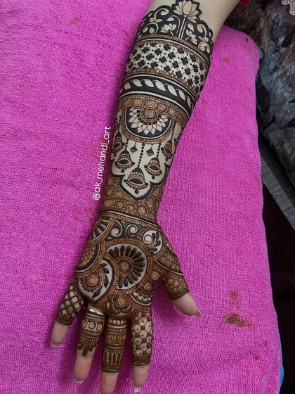 A full bridal design with hanging bell motifs on the arm. This is a beautiful example of incorporating traditional jewelry elements into the mehndi.