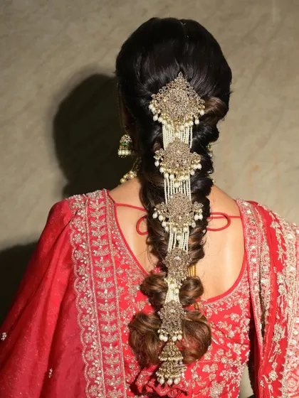 A view of the stunning bridal braid, adorned with intricate hair accessories. This hairstyle is a work of art, perfectly complementing the traditional red outfit.