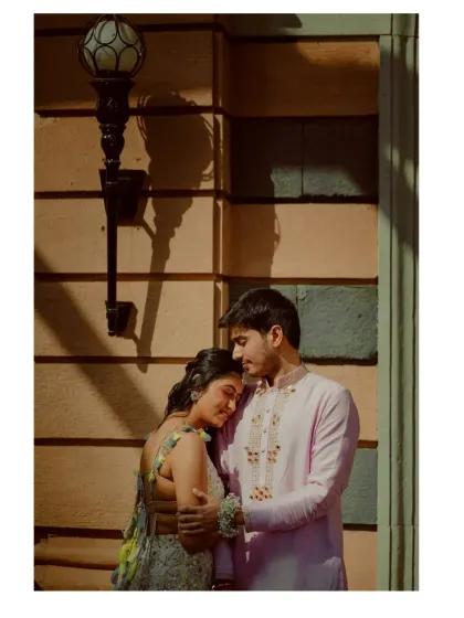 A quiet, intimate moment of the bride resting her head on the groom's shoulder. The warm sunlight and shadows create a beautiful, artistic composition.